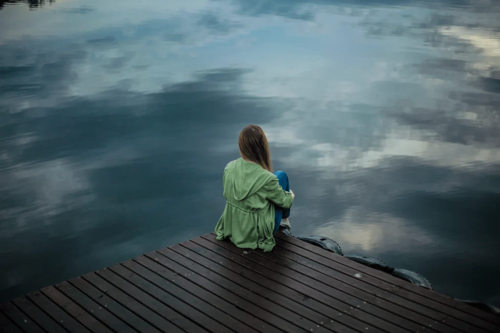 signs of deep emotional trauma a girl sitting in looking at the water